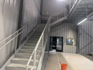 Steel staircase with cable railings in industrial warehouse interior
