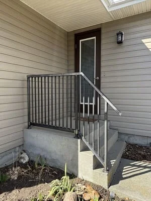 Steel railing and handrail on residential entry stairs with vertical pickets