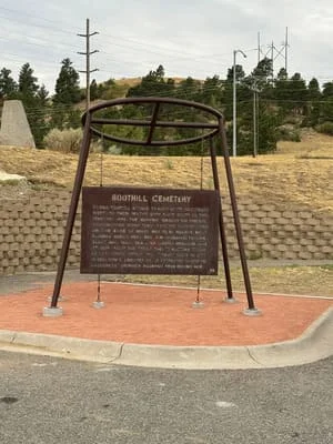 Steel fire ring monument with circular frame and cross-bracing on welded base with plaque