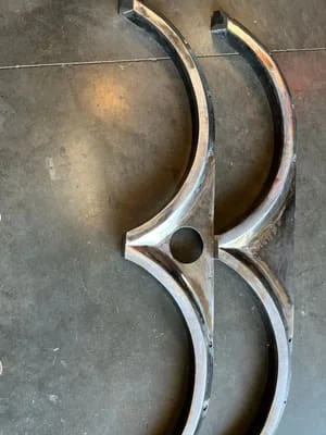 Two curved steel scroll brackets with welded construction and polished finish