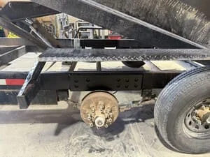Steel dump trailer with angled bed, hydraulic cylinders, and reinforced frame construction