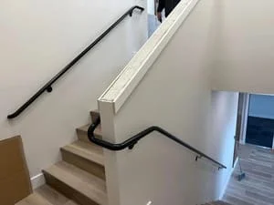Black powder-coated steel stair railing with mounting brackets on interior staircase
