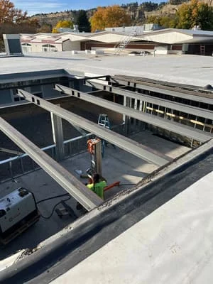 Steel I-beams and columns installed on commercial roof structure during construction