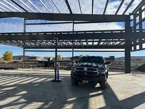Steel carport frame with welded structural members and horizontal roof beams
