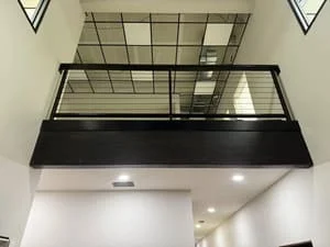 Steel mezzanine platform with glass railing, black handrails, and recessed lighting
