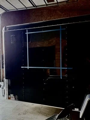 Dark powder-coated steel enclosed trailer with welded frame and reinforced door structure