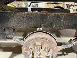 Trailer axle assembly with brake drum, spindle, and suspension components installed