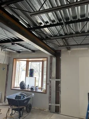Steel I-beam frame with corrugated metal roof panels in industrial interior space