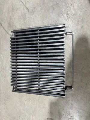 Welded steel grate with parallel bars and frame mounting brackets on concrete surface