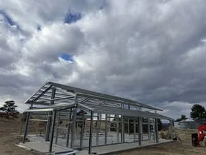 Steel frame structure with welded beams, columns, and glass panel installation during construction