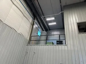 Welded steel mezzanine platform with metal grating decking and safety railings in industrial warehouse